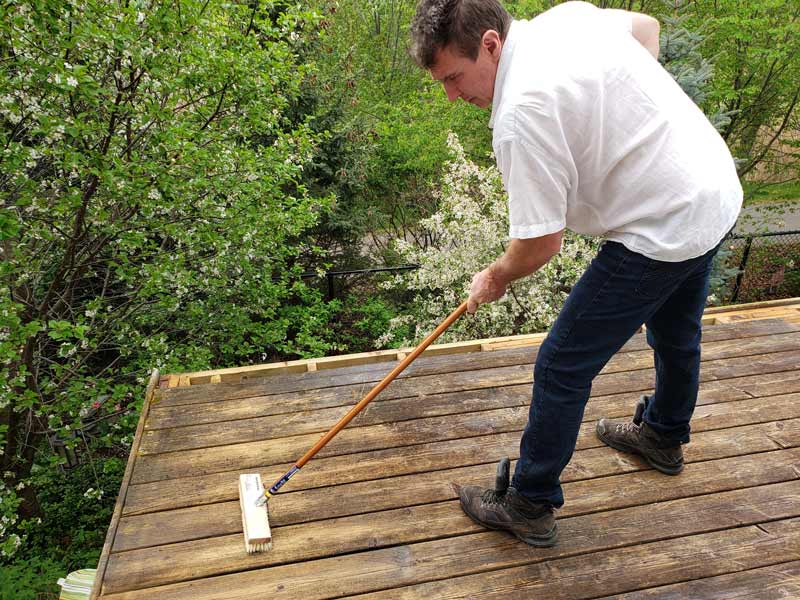 homme nettoyant une terrasse en bois